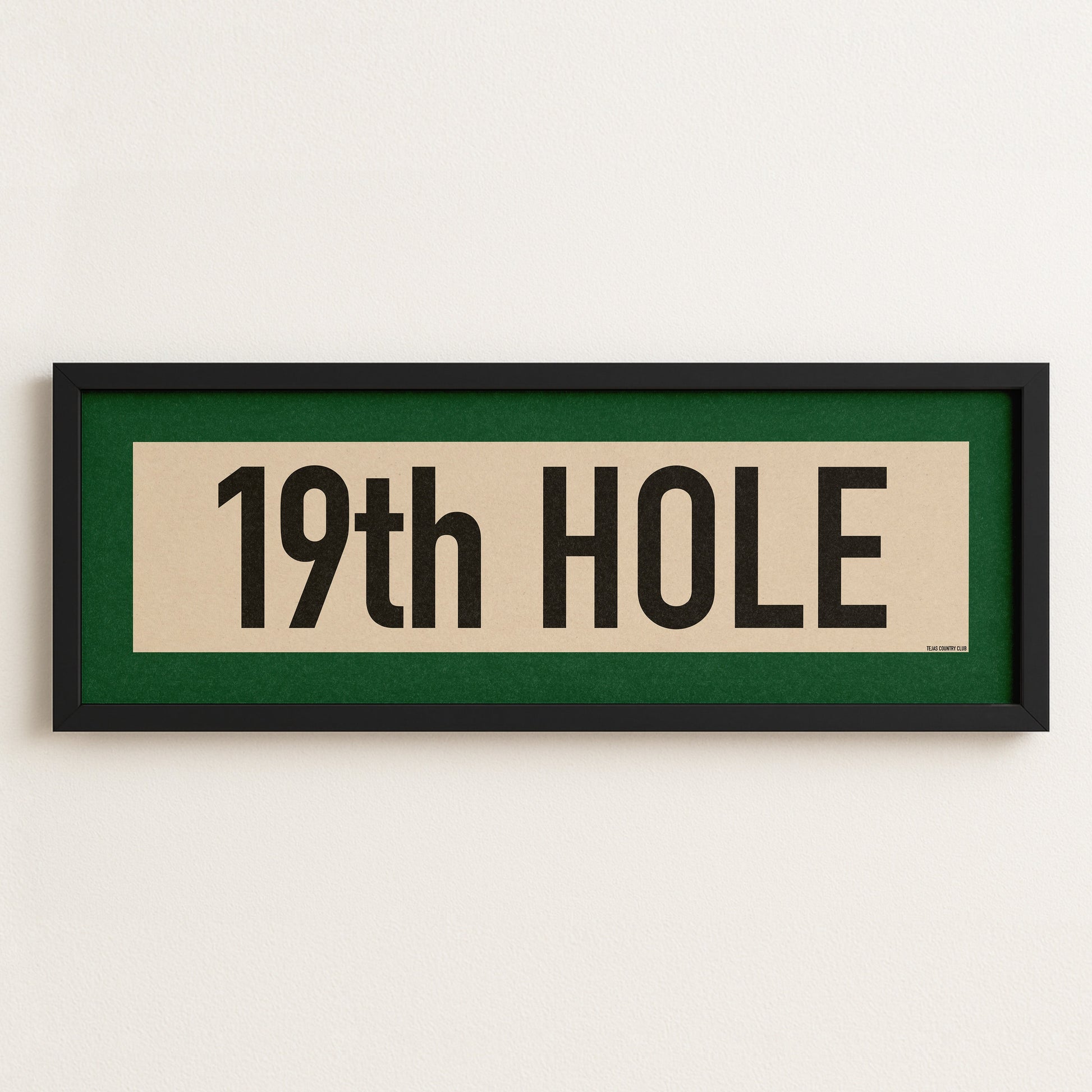 Framed sign with '19th Hole' text on a white wall