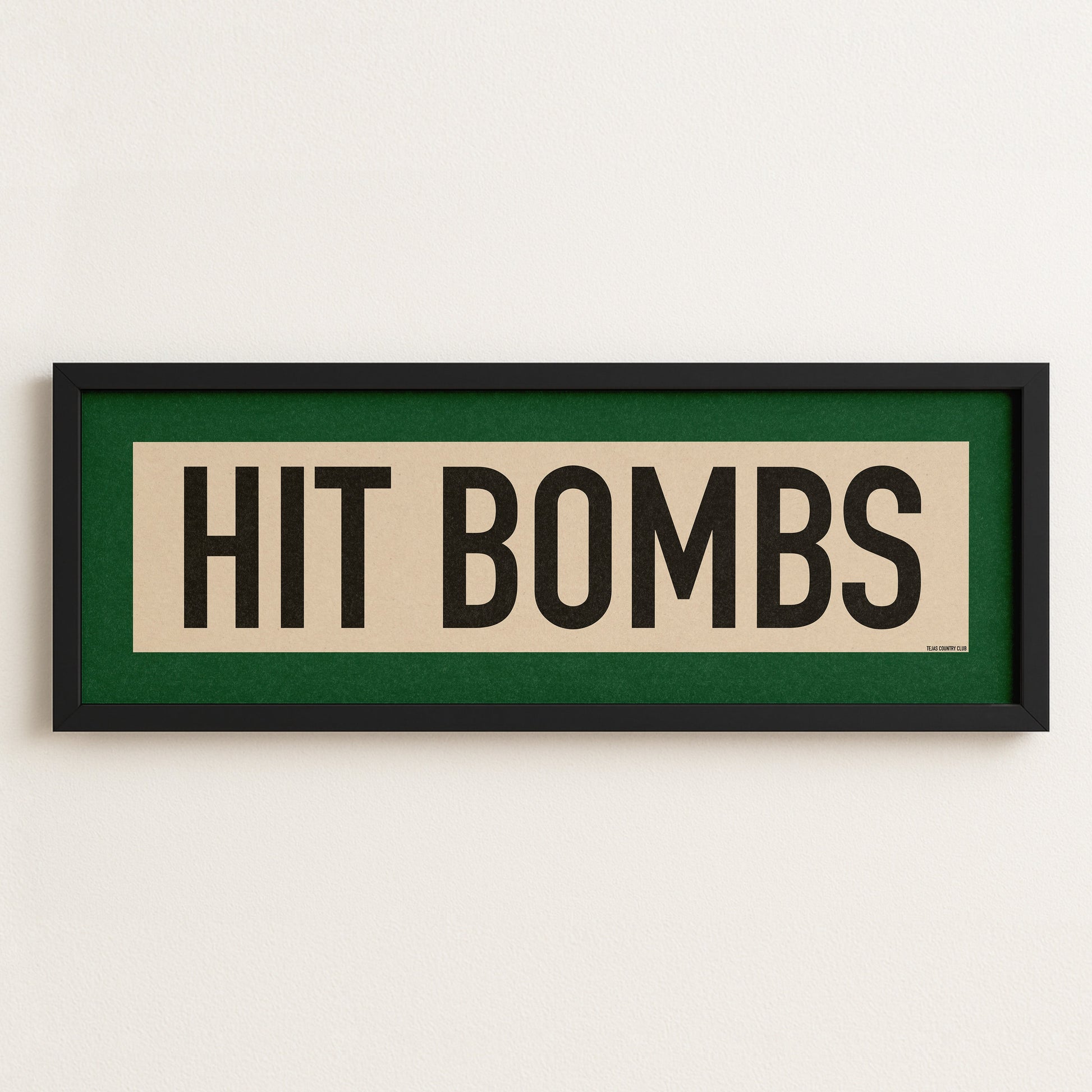 Framed sign with 'HIT BOMBS' text on a white wall