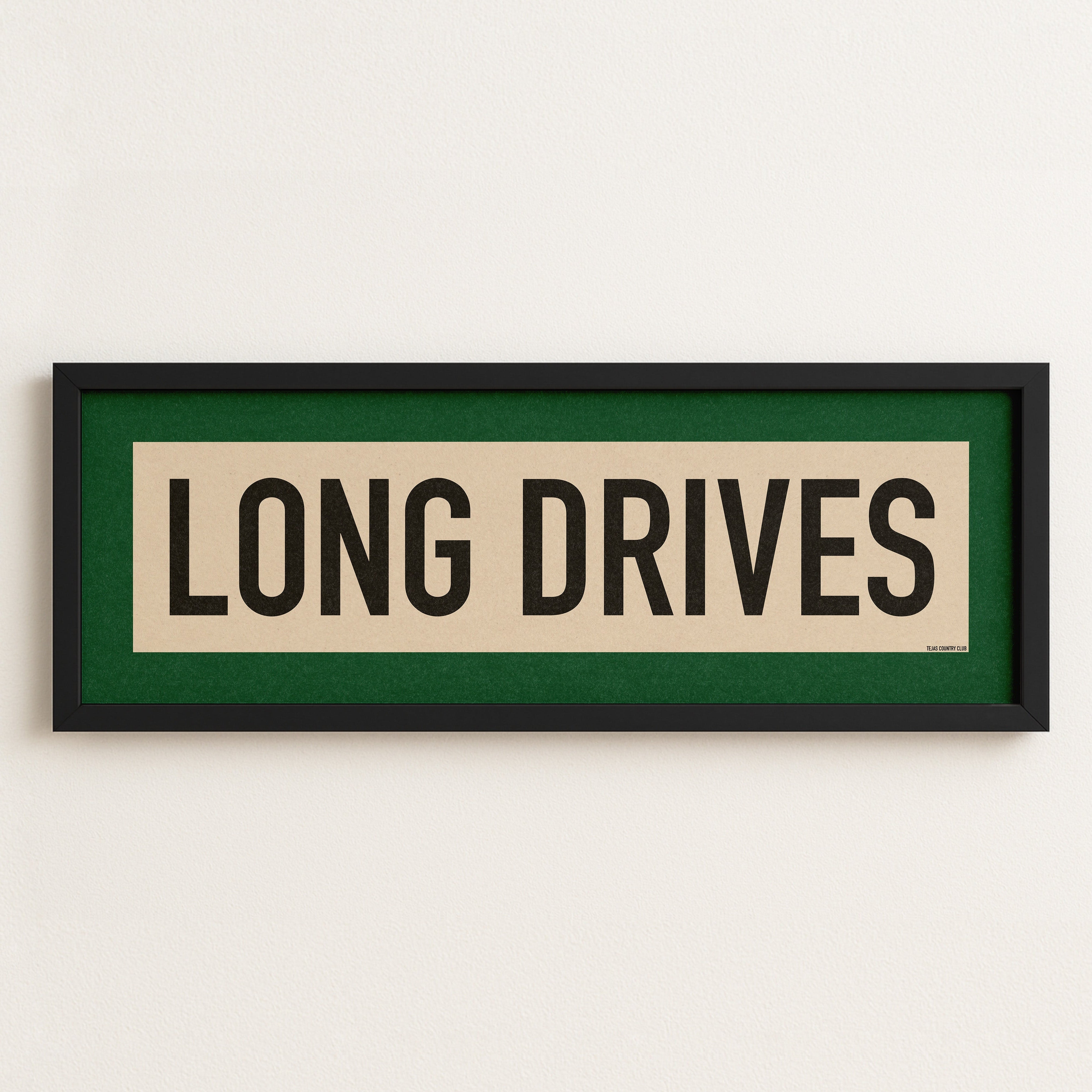 Framed sign with 'LONG DRIVES' text on a white wall