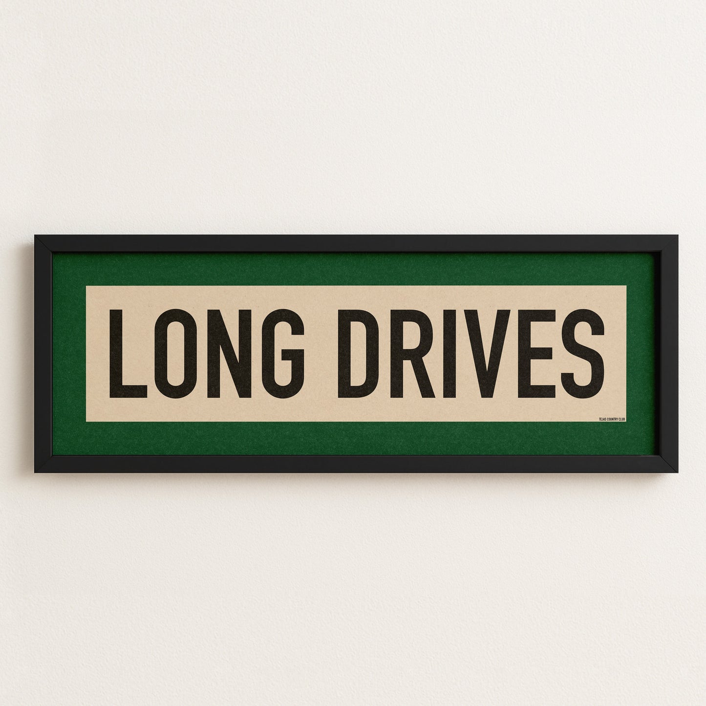 Framed sign with 'LONG DRIVES' text on a white wall