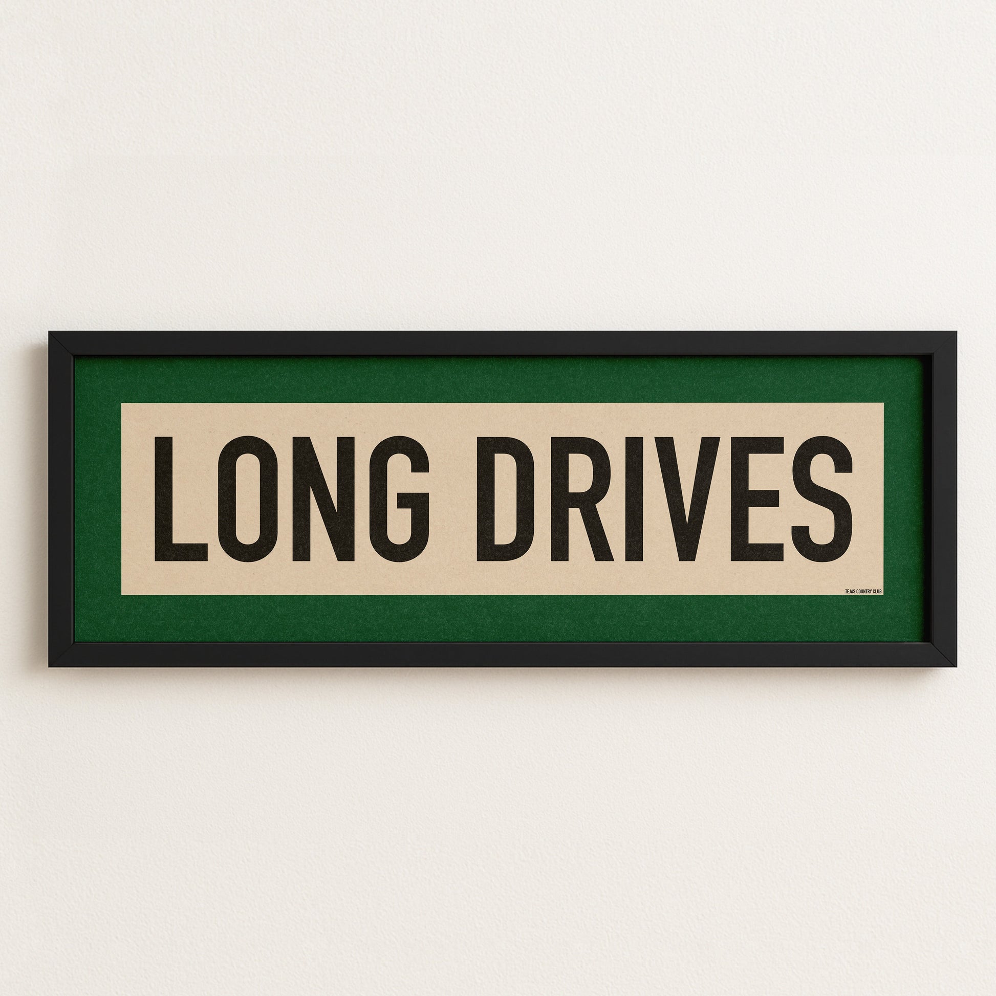 Framed sign with 'LONG DRIVES' text on a white wall