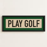 Framed sign with 'PLAY GOLF' text on a white wall
