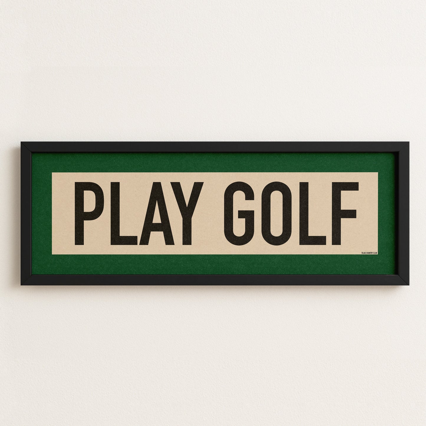 Framed sign with 'PLAY GOLF' text on a white wall