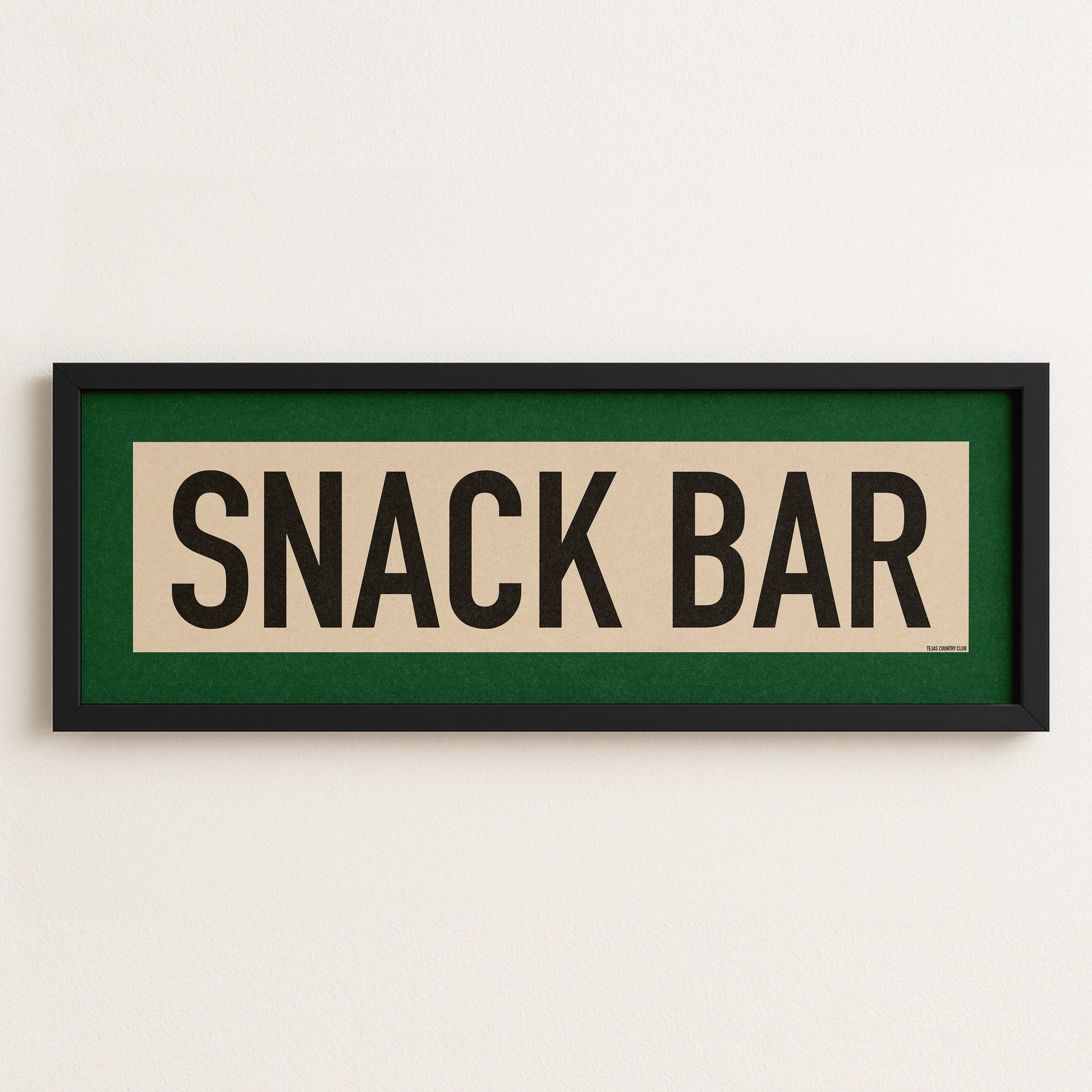 Framed sign with 'SNACK BAR' text on a white wall