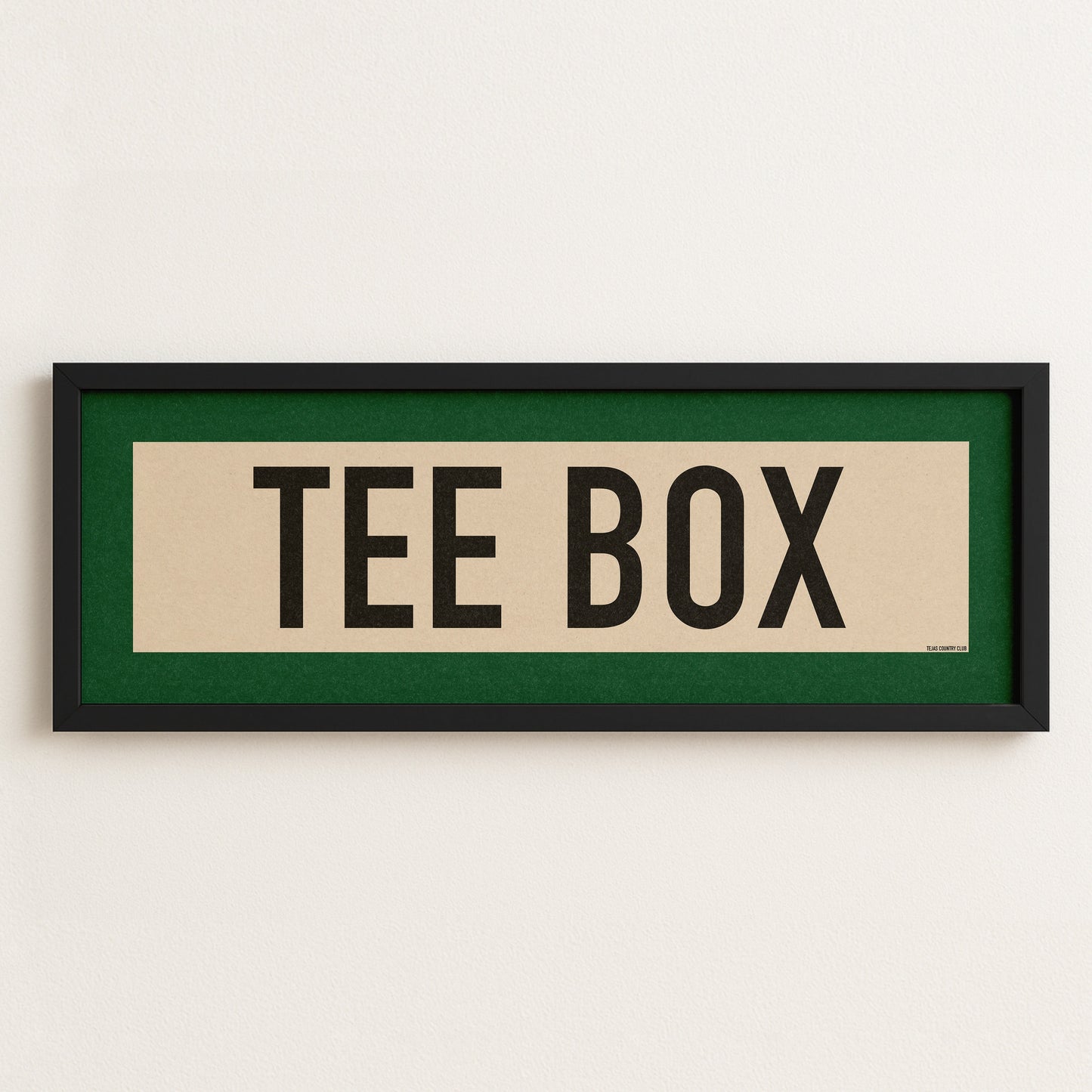 Framed sign with 'TEE BOX' text on a white wall