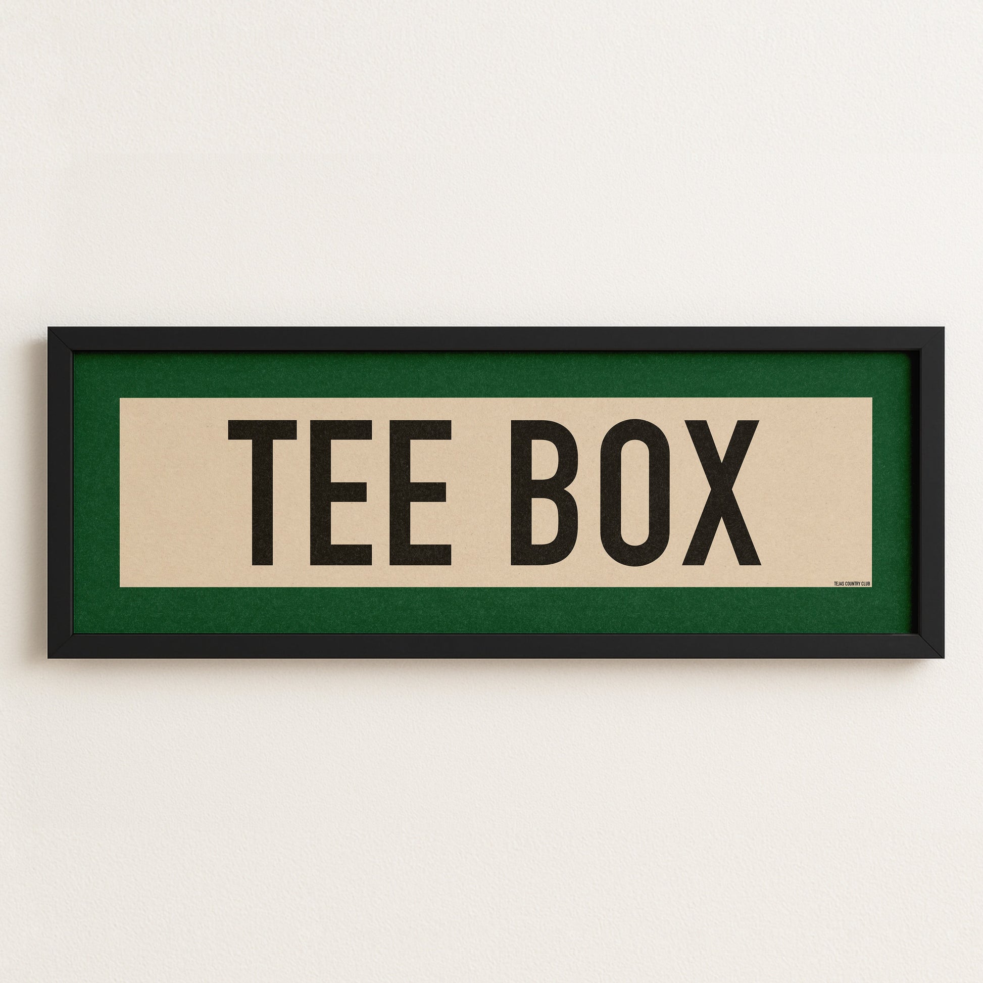 Framed sign with 'TEE BOX' text on a white wall